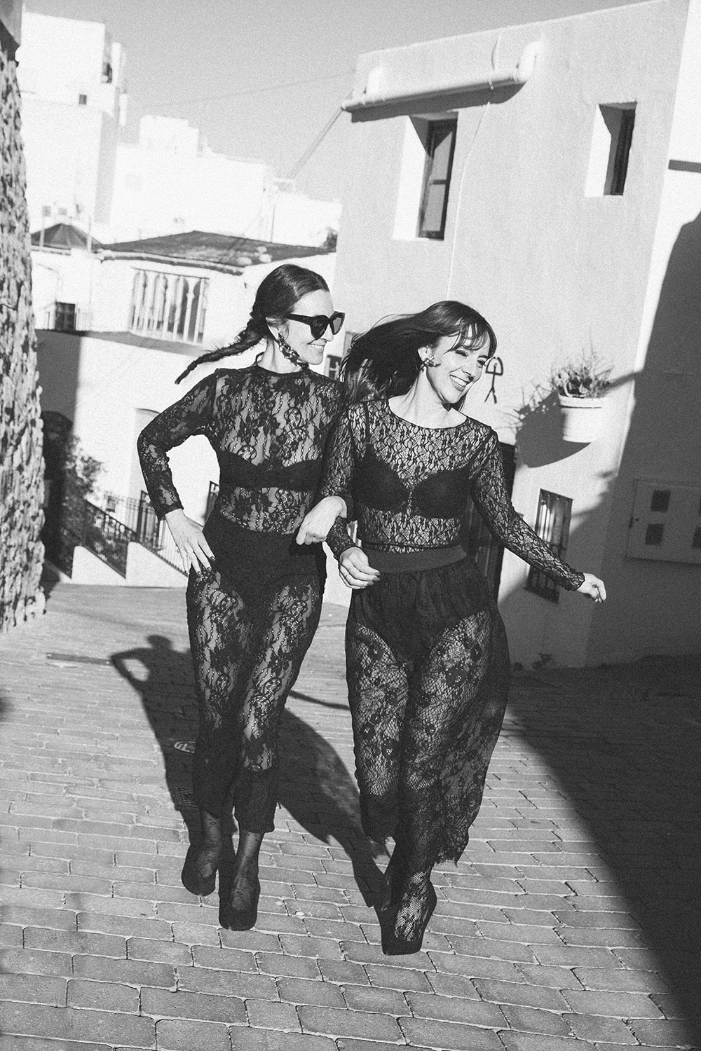 Cristina y Gloria Navarro posando con vestidos de encaje negro y transparencias en una calle blanca de Mojácar para su sesión de Navidad 2025, Cal y Encanto.