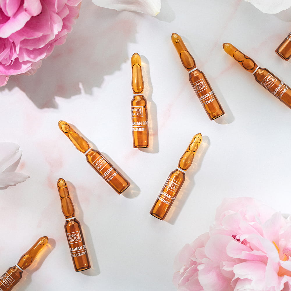 Fotografía de ampollas Arôms Natur en composición floral sobre fondo claro