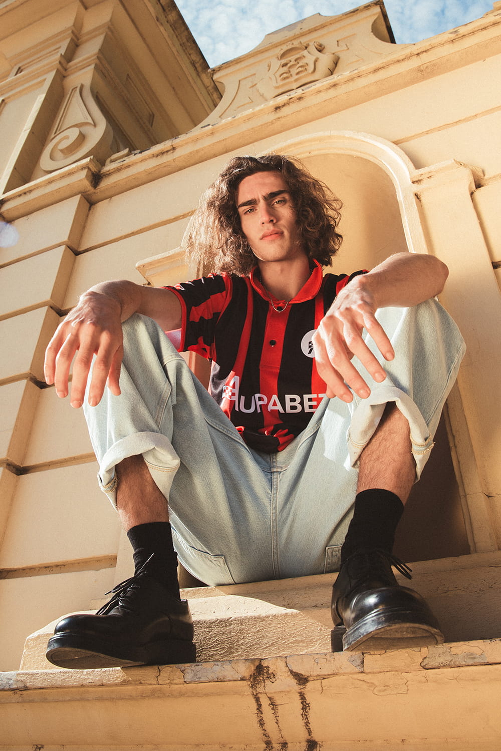 Fotografía de moda editorial con modelo masculino posando en exterior con camiseta corporativa de marca