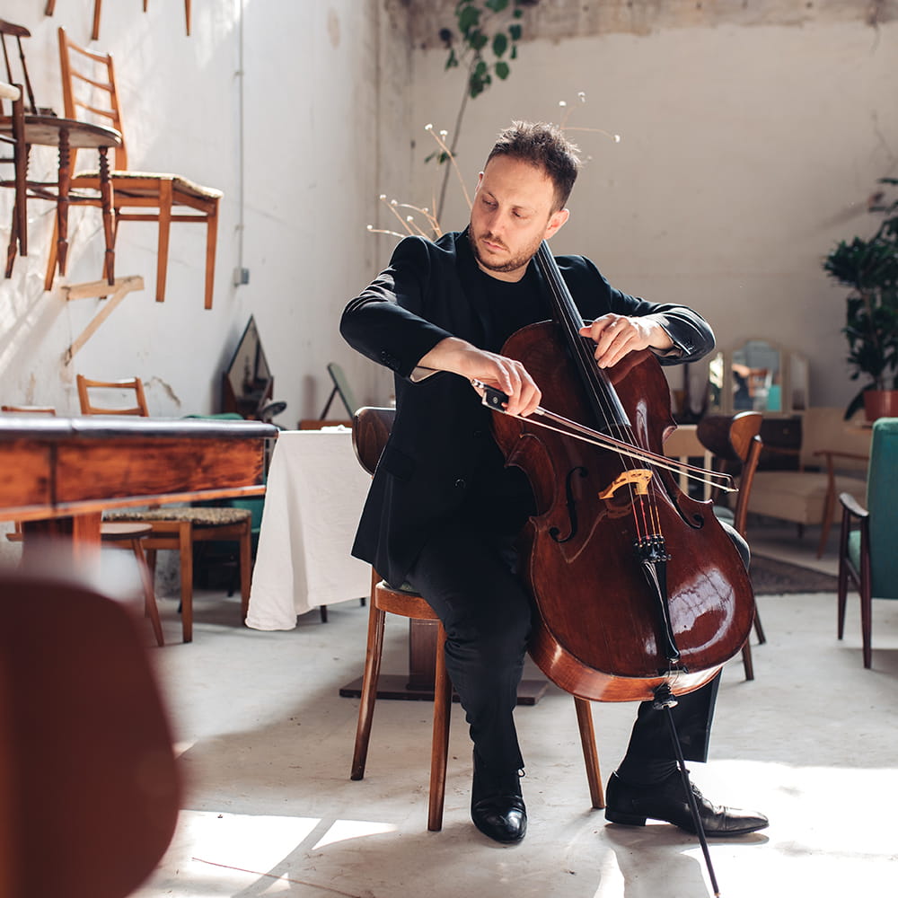 Músico tocando el violonchelo en una sesión de fotografía de marca personal en un espacio luminoso