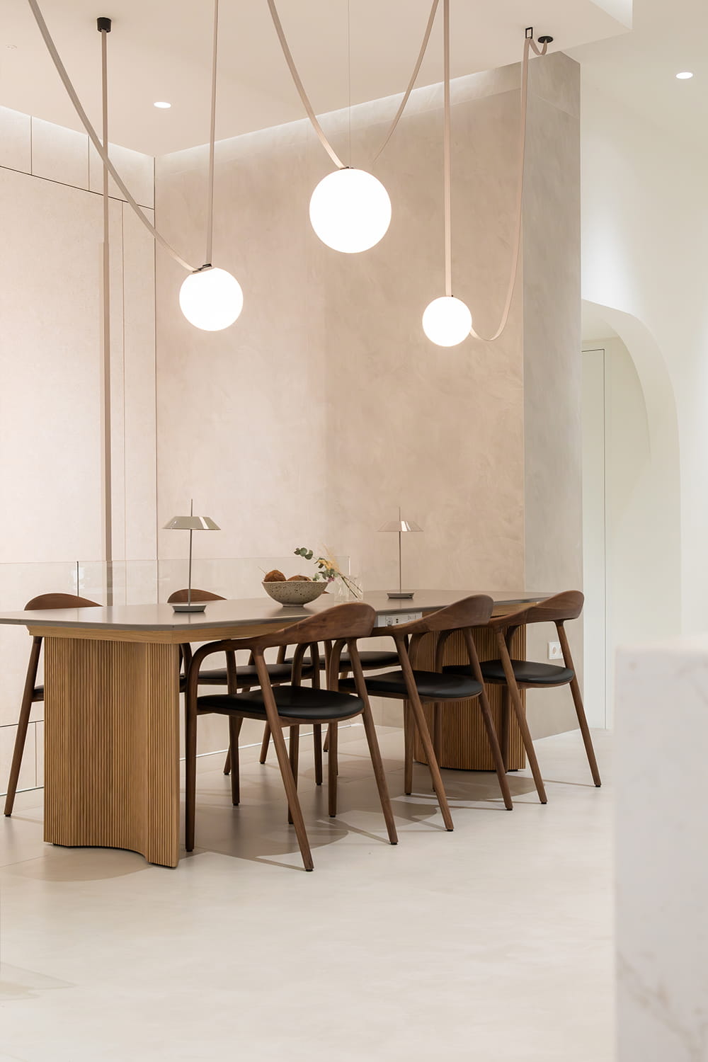 Fotografía de interiores de comedor moderno con mesa de madera, sillas de diseño y lámparas colgantes