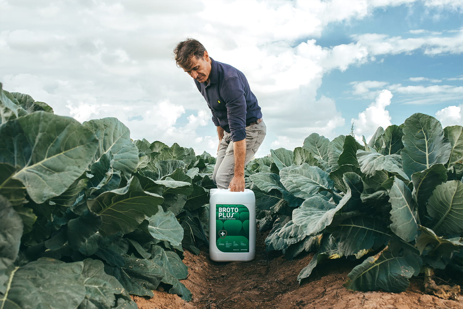 Agricultor en un cultivo junto a un fertilizante de la marca Broto Plus en el campo