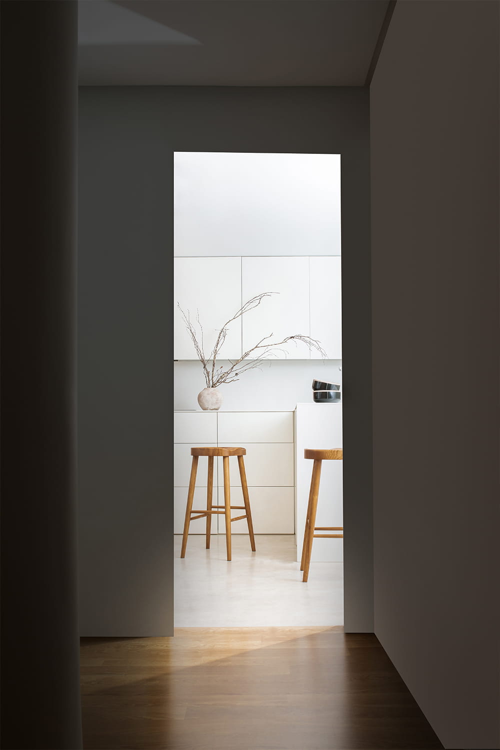Fotografía de arquitectura interior con vista a cocina minimalista desde pasillo