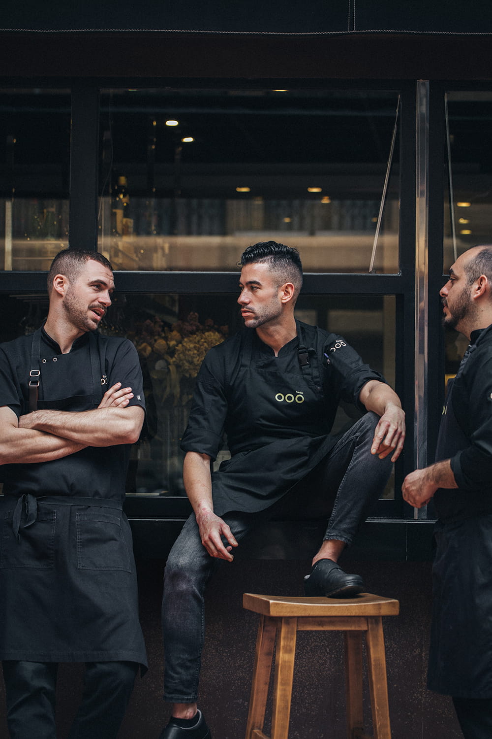 Fotografía gastronómica del equipo del restaurante Por Herencia descansando tras servicio frente al local con uniformes de cocina