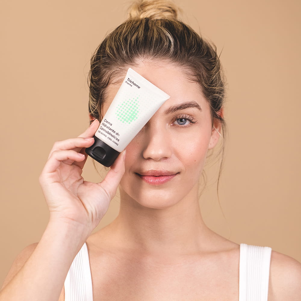 Fotografía beauty en estudio con modelo sosteniendo crema cosmética para campaña de cuidado facial