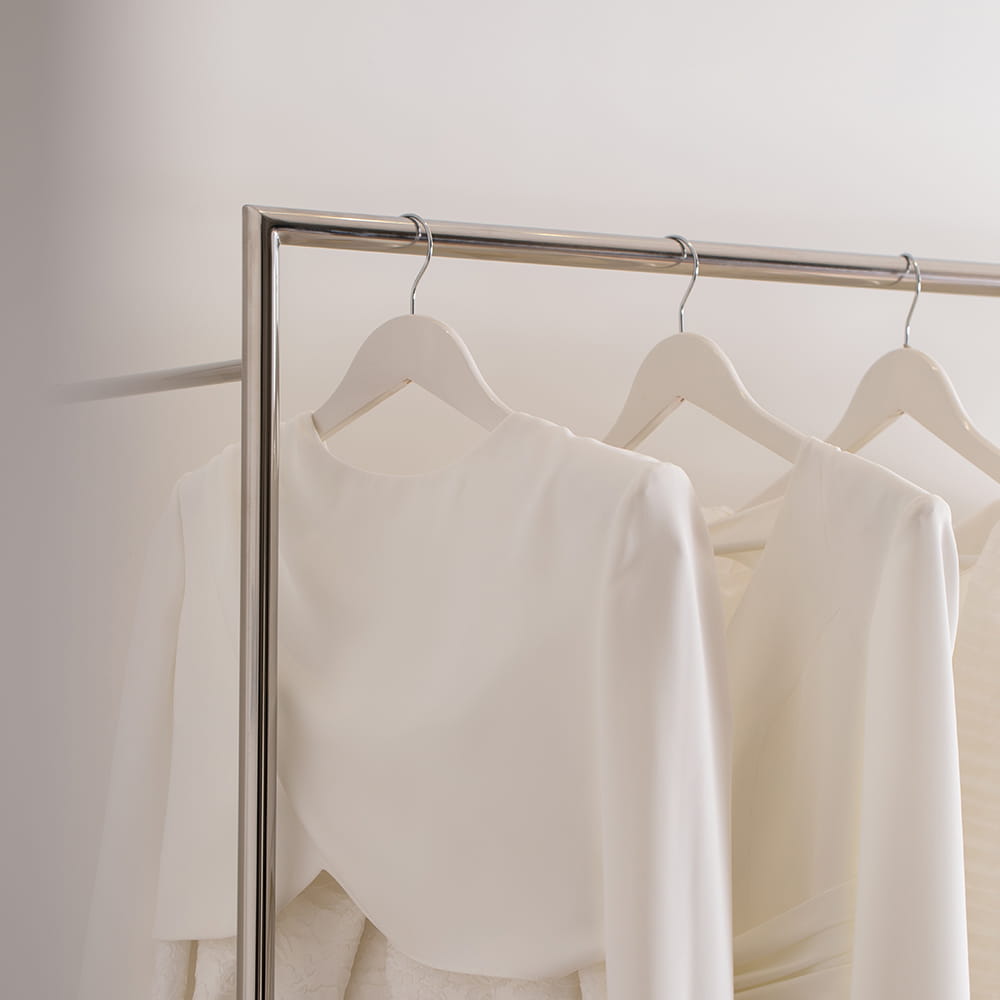 Vestidos de novia minimalistas colgados en perchero en tienda de moda nupcial