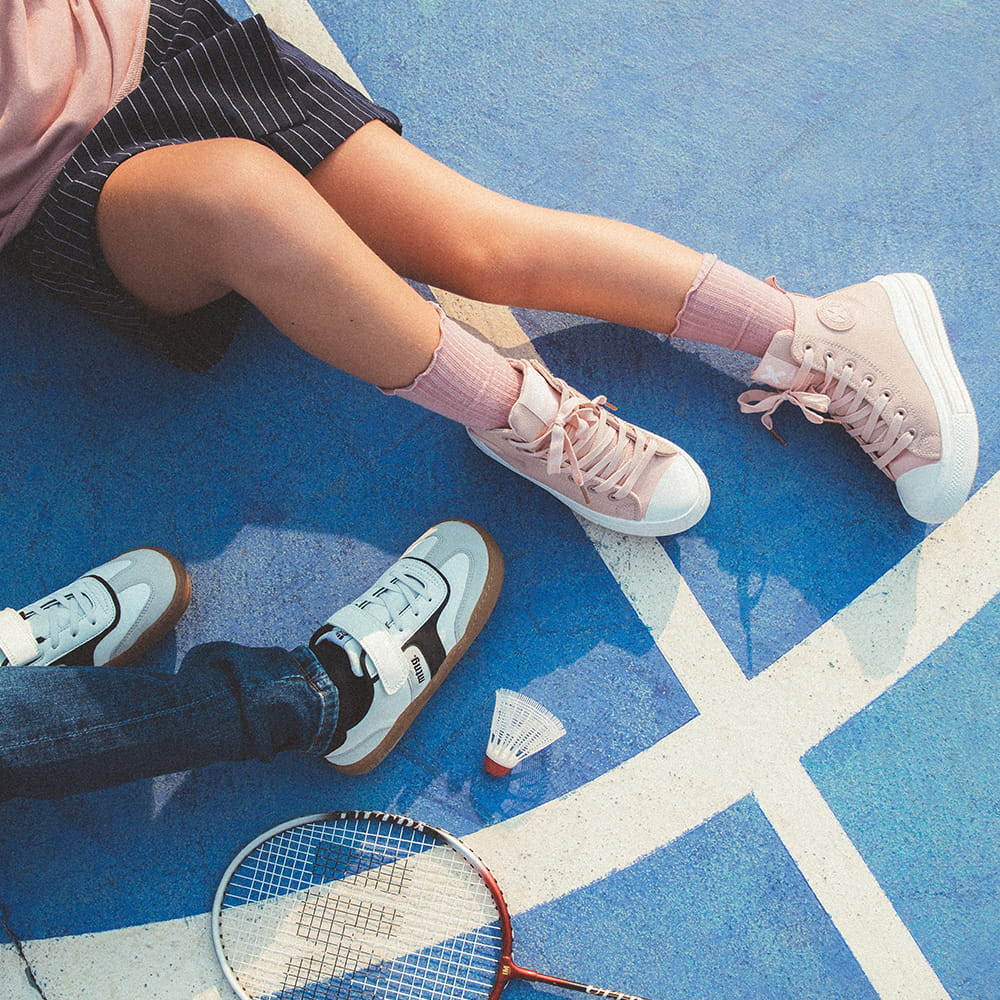 Fotografía de moda infantil en pista deportiva con niños luciendo zapatillas para campaña de calzado