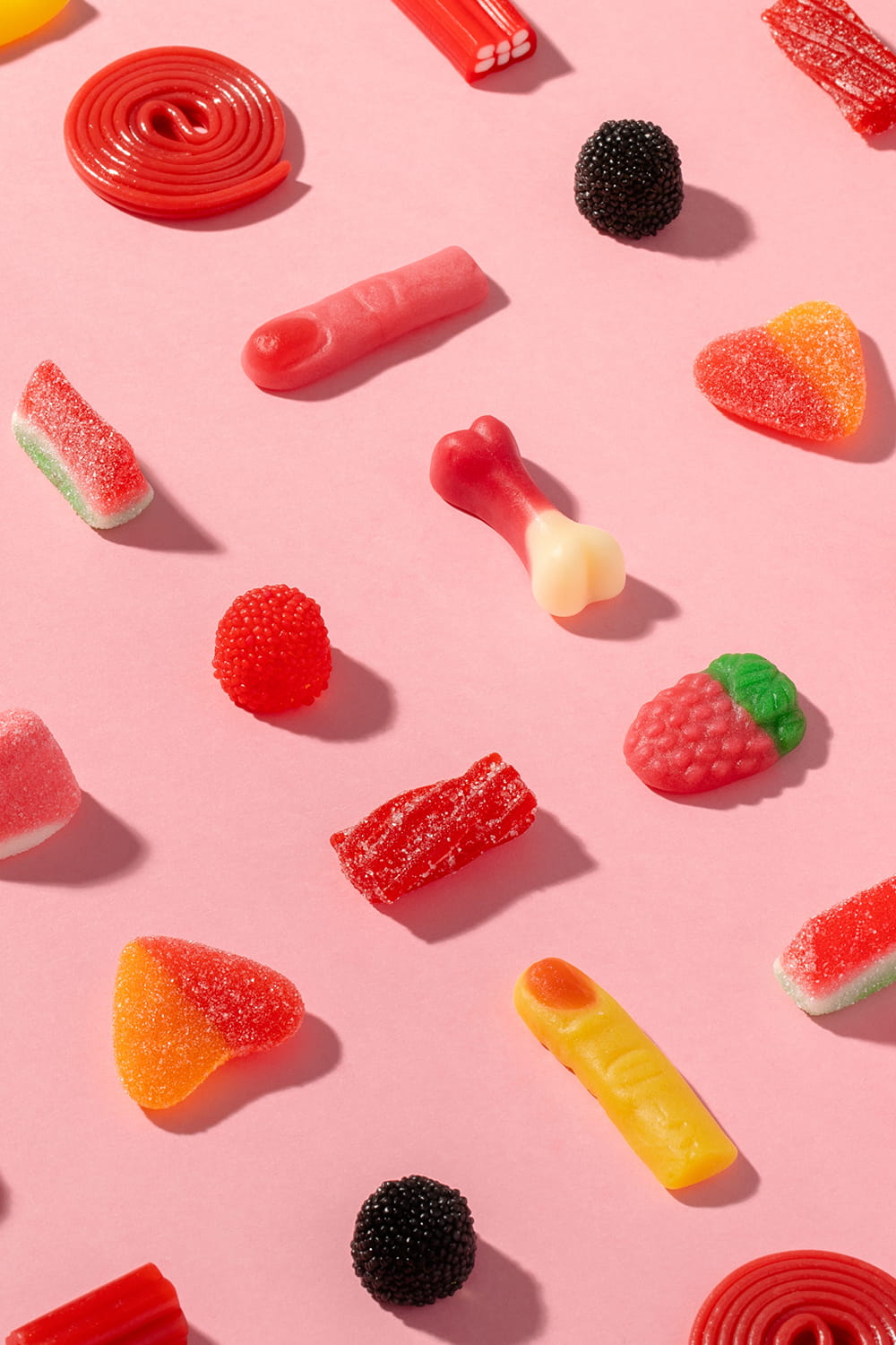 Fotografía publicitaria de golosinas sobre fondo rosa para packaging de bolsa de chucherías Eroski