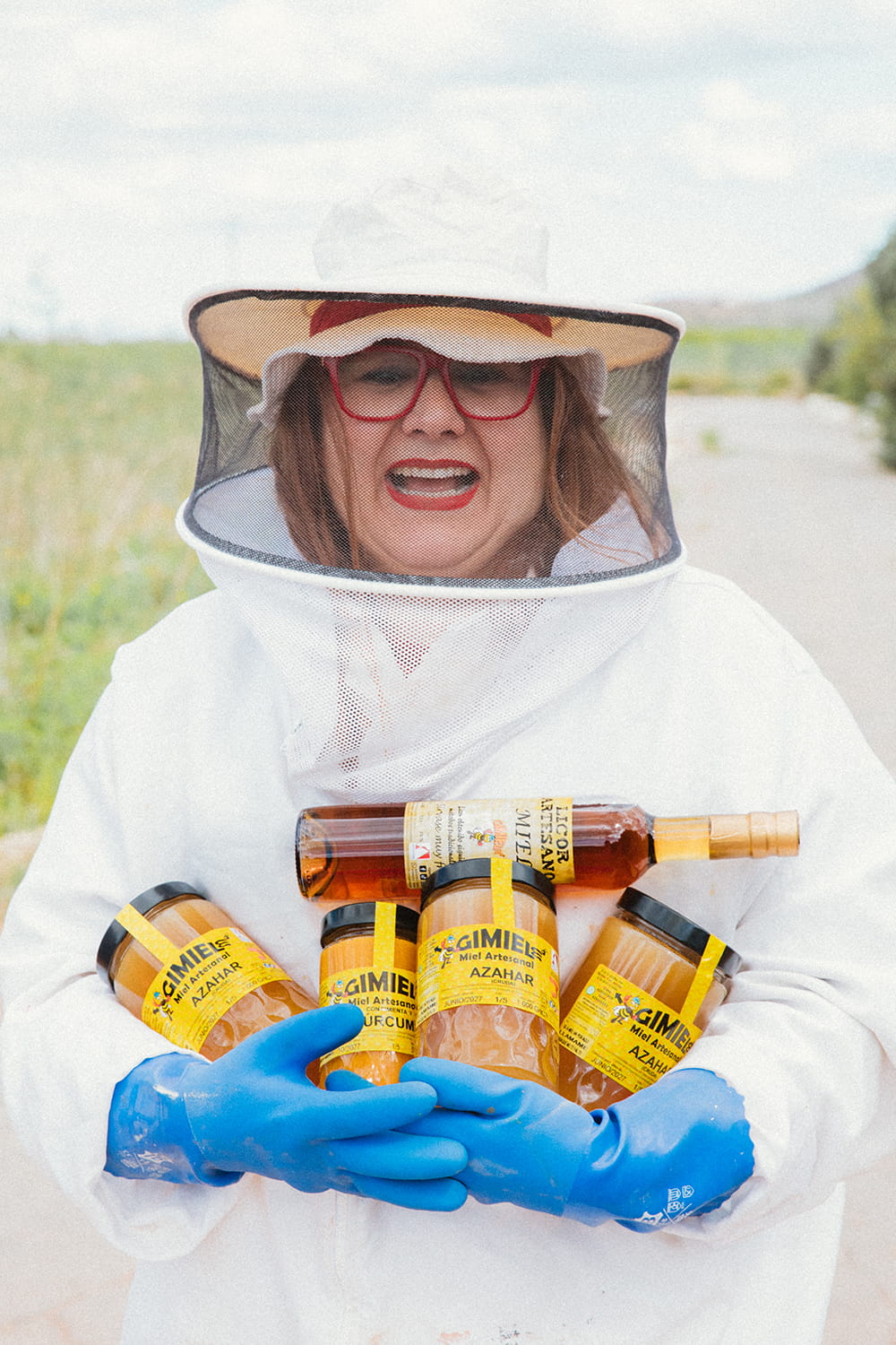 Elena, apicultora de Gimiele, con traje protector sosteniendo tarros de miel artesanal en el campo de Cartagena