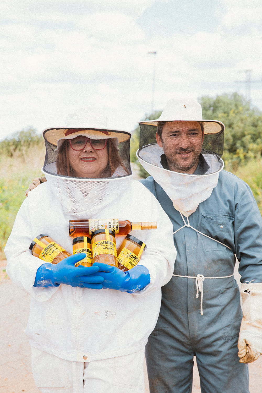 Elena y Ginés, apicultores de Gimiele, con traje protector mostrando tarros de miel artesanal en el campo de Cartagena