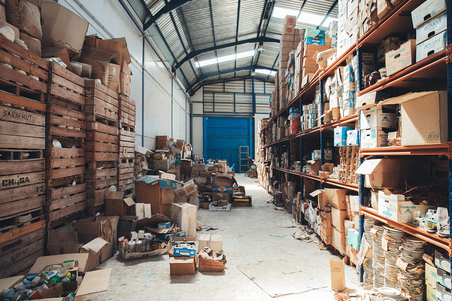 Interior del almacén de Cristal Antiguo en Lorquí con estanterías llenas de cajas de menaje y loza del siglo XX