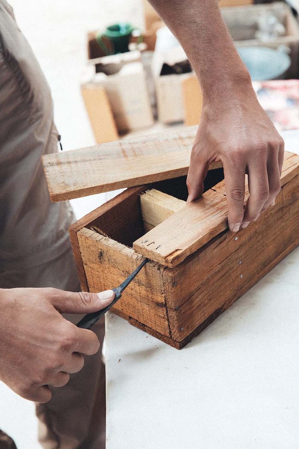 Primer plano de las manos de Juan Bohajar abriendo una caja de madera antigua cerrada con clavos, usando un punzón de metal