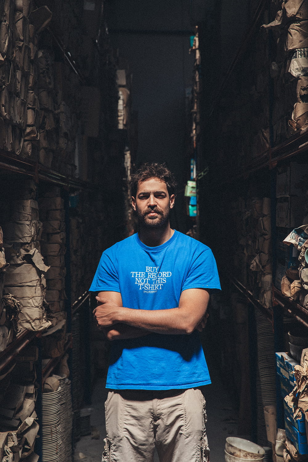 Primer plano de Juan Bohajar con los brazos cruzados en un pasillo estrecho del almacén de Cristal Antiguo en Lorquí.